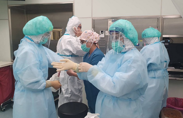 手術前,所有手術室工作人員穿著防護衣外加防水隔離衣,並戴上兩層手套、護目鏡與面罩。(臺中慈濟醫院提供)