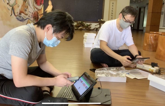 青年小組鄭銘涵(左)協助檢查測試二手平板電腦。(攝影者:鍾宛吟,地點:慈濟馬六甲分會文化廳、日期:2021/07/24)