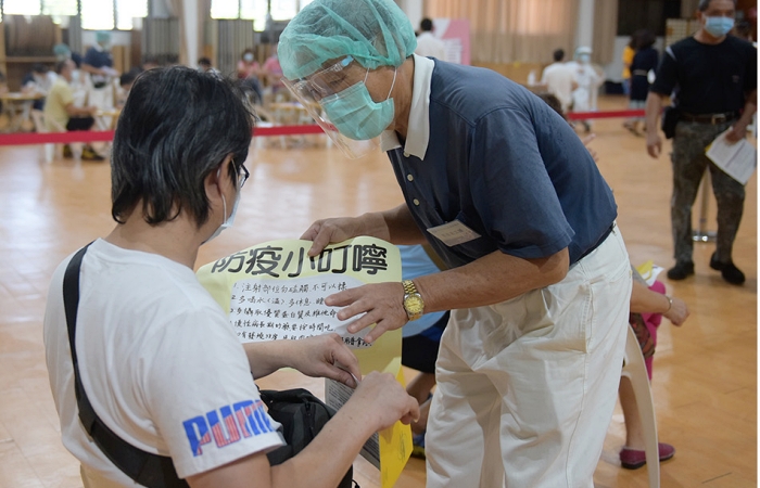 慈濟志工為休息區民眾說明疫苗接種後的注意事項。(照片:慈濟志工提供)