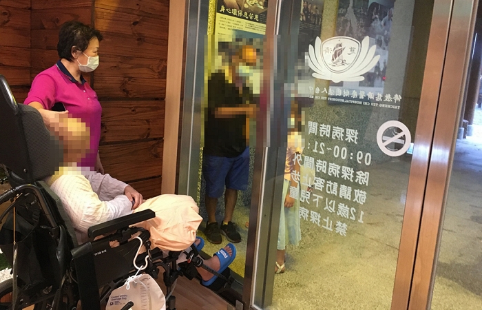 病人與家人隔著落地窗見面,用手機擴音講講話,雖然握不到手,但溫暖卻在彼此心中流動。(攝影者:黃美玲,地點:臺中慈院,日期:2021/06/09)