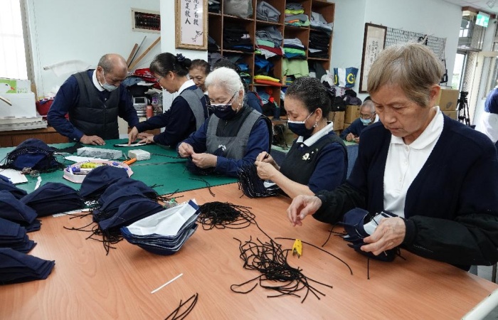 家住土城的賴明霞(右),每天早上花一小時換兩班車來到園區,幫忙剪線頭線尾。她感恩有因緣回到慈濟道場,日子愈過愈自在。(攝影者:黃秀琴,地點:板穚志業園區,日期:2020/04/14)
